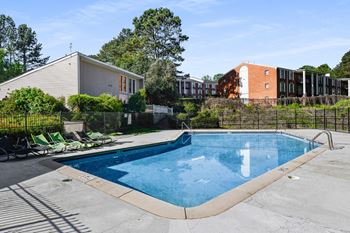 a swimming pool with chairs and a building in the background at Premier Apartments, Georgia, 30168